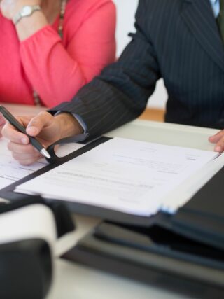 Two people signing a business document to open a business bank account.